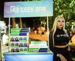 promotora al lado de un stand de geek bar con productos de vapeo